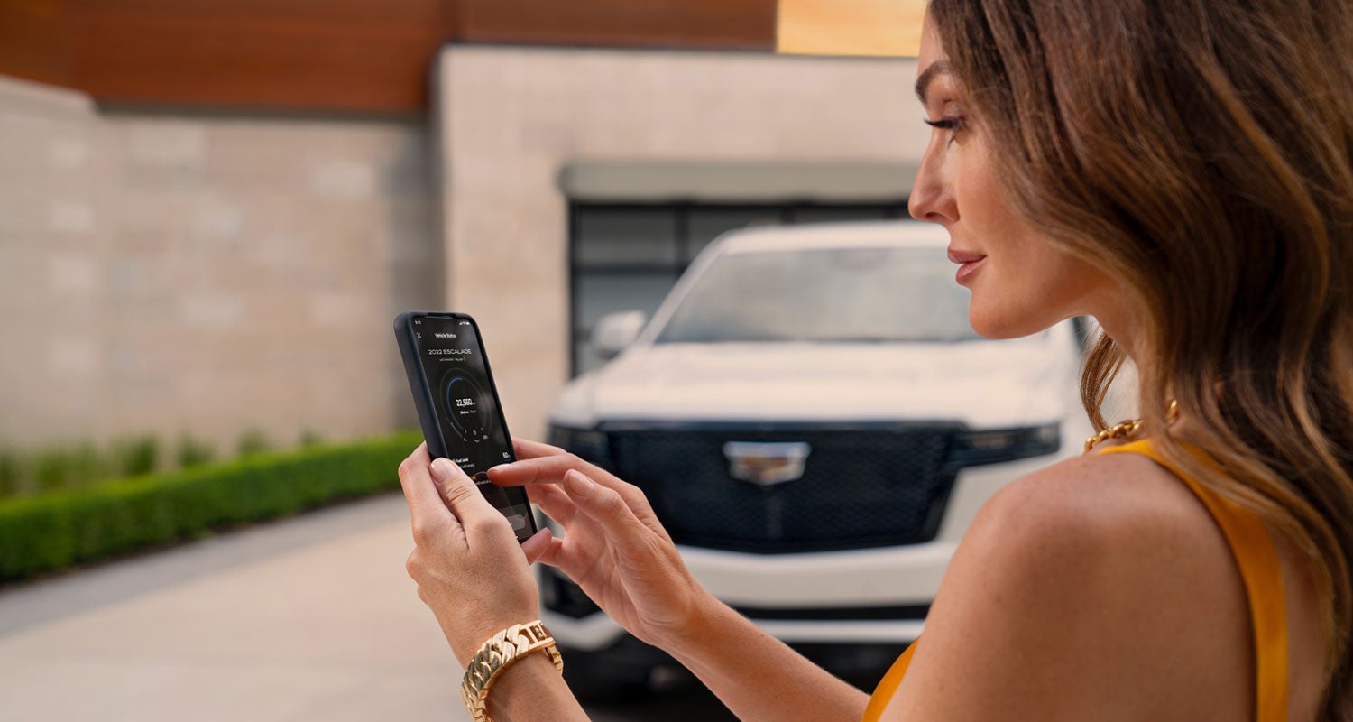 lady checking her mobile with a Cadillac vehicle background | Dimmitt Cadillac of St. Petersburg in Pinellas Park FL